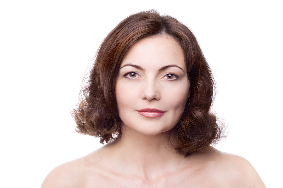 beautiful middle-aged woman with bare shoulders isolated on white; natural-looking results with cosmetic surgery